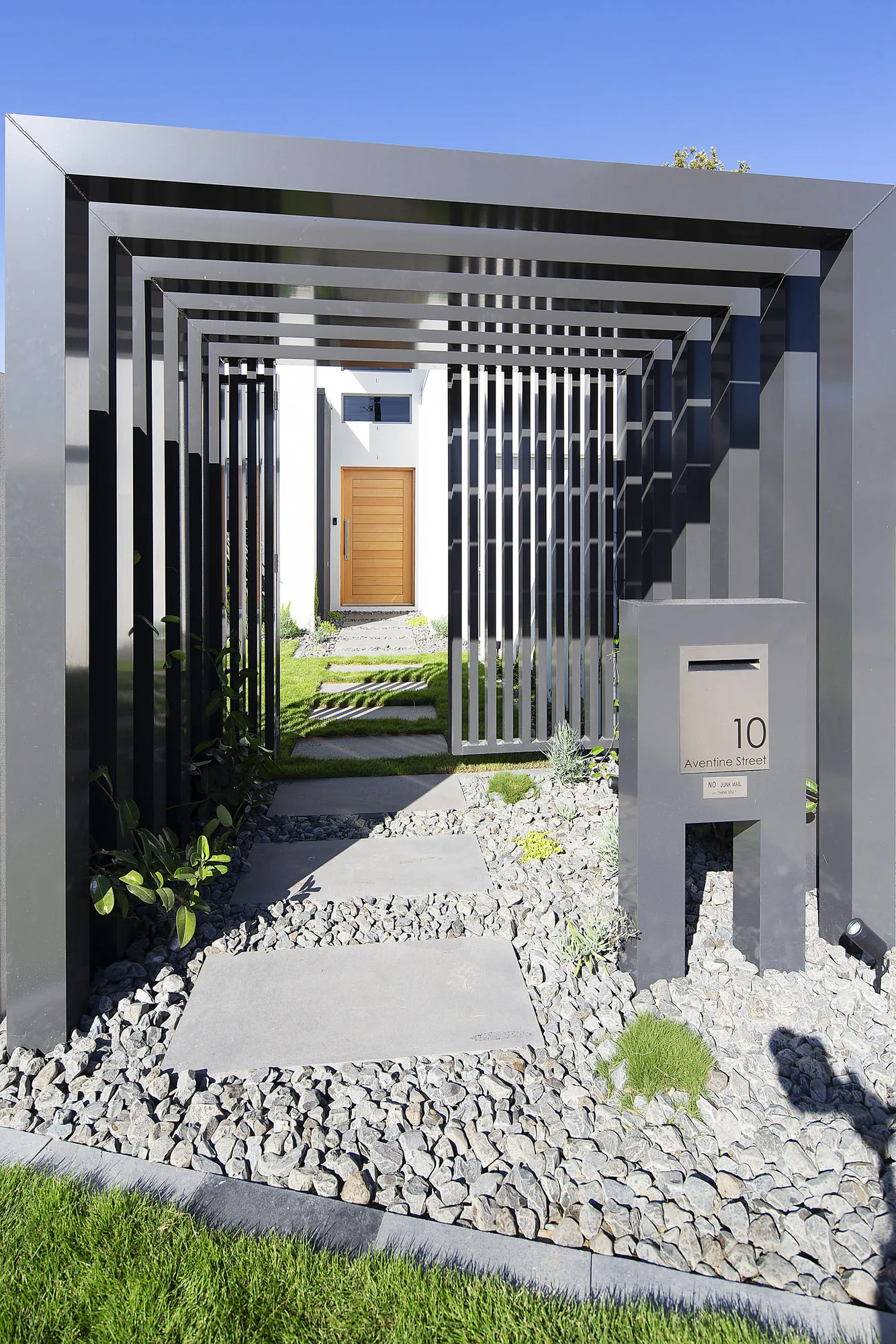Steel pergola walkway with timber posts framing a narrow side entry path