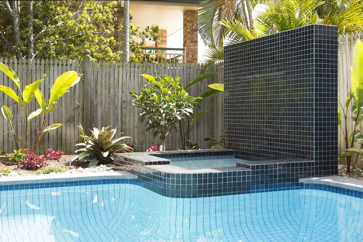 Tiled water feature wall cascading into a pool framed by tropical banana leaf planting