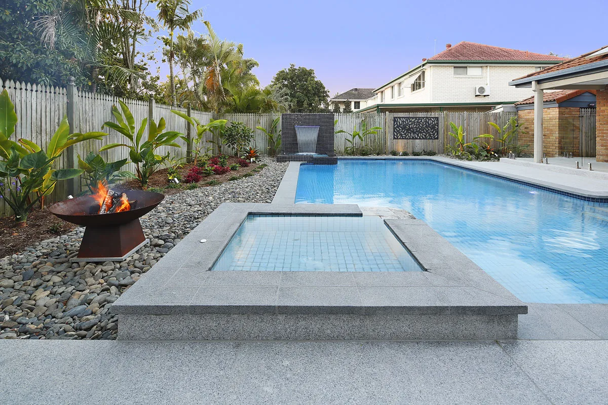 Established tiled water feature wall and pool set within a mature tropical garden