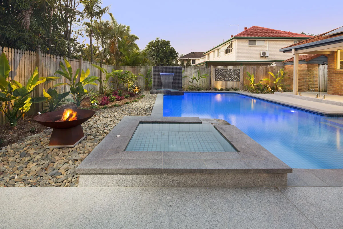 Twilight pool and spa with palm silhouettes against a darkening sky