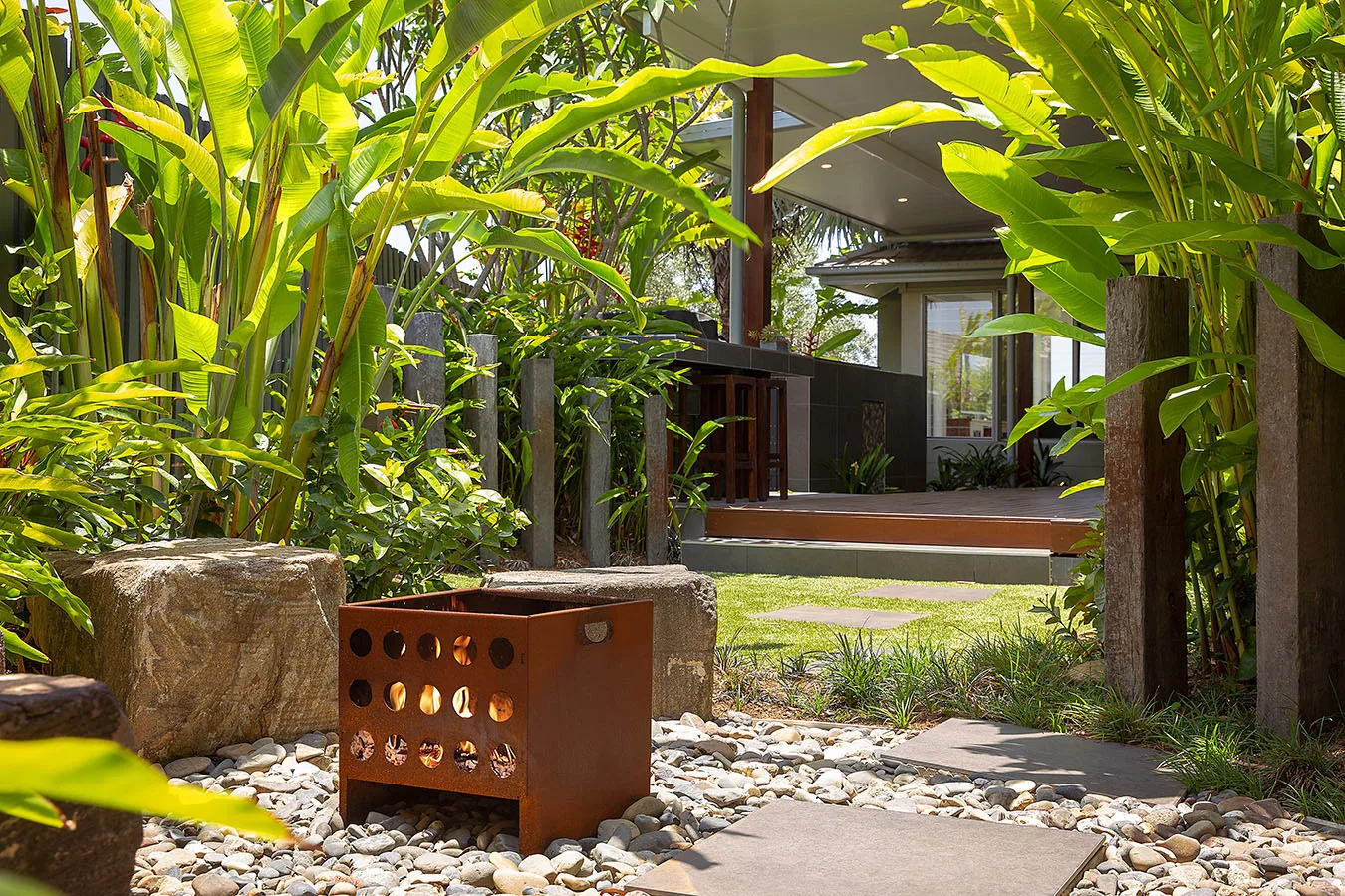 Banana and heliconia foliage framing a view through to an outdoor kitchen counter and covered deck