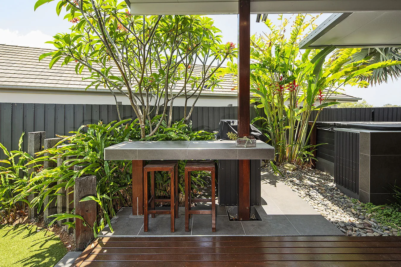 Outdoor kitchen counter framed by golden cane palms and a flowering frangipani