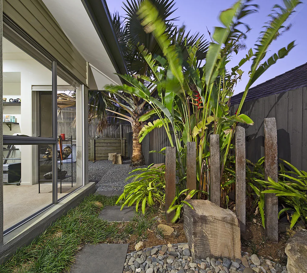 Glass sliding door beside a palm and a timber post at dusk